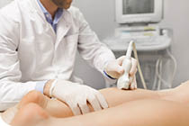 Orthopedist doctor doing ultrasound examination of patient's leg veins in his office  Young woman passing ultrasound scan in clinic  Doctor work  Medical research 