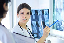 Two smiling doctors pointing at x-rays in a hospital consulting room