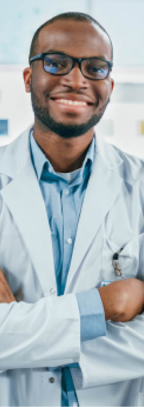 Pharmacy: Professional Confident Black Pharmacist Wearing Lab Coat and Glasses, Crosses Arms and Looks at Camera Smiling Charmingly. Druggist in Drugstore Store with Shelves Health Care Products