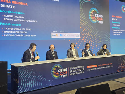 Quatro adultos sentados em uma mesa de debate durante o 4º Congresso Brasileiro de Medicina Geral com telas azuis ao fundo exibindo informa es do evento.  Descri  o gerada por IA